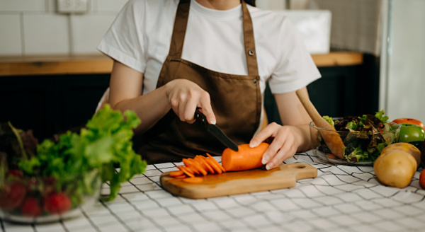 Hands preparing vegetables on a cutting board in a bright kitchen